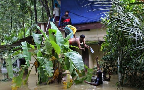 Volunteers reach out to stranded people with food supplies in a flooded area in Chengannur in the southern state of Kerala - Credit: Aijaz Rahi/ AP