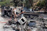 <p>Men spray water on charred debris of vehicles that were destroyed by fire in a parking lot for camping cars in Bormes-les-Mimosas, in the Var department, France, July 26, 2017, after firefighters evacuated thousands of campers and local residents when a wildfire broke out on France’s tourist-thronged Riviera coast overnight. (Jean-Paul Pelissier/Reuters) </p>