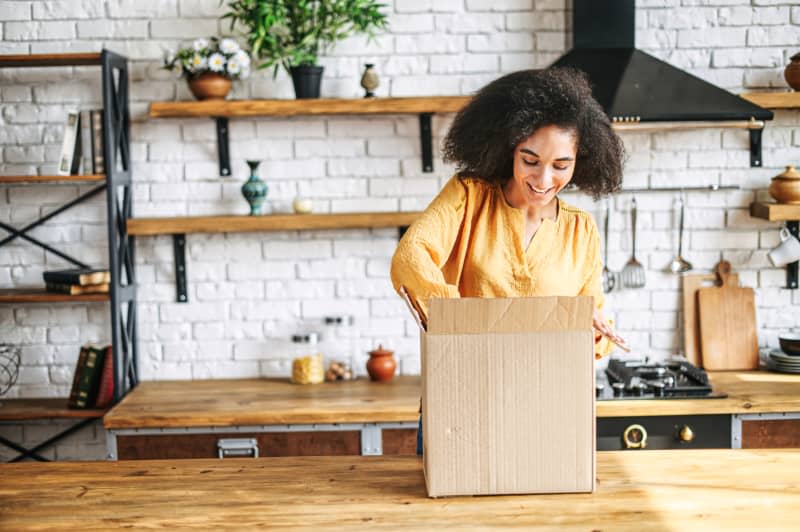 Attractive woman unpacks a box in the kitchen