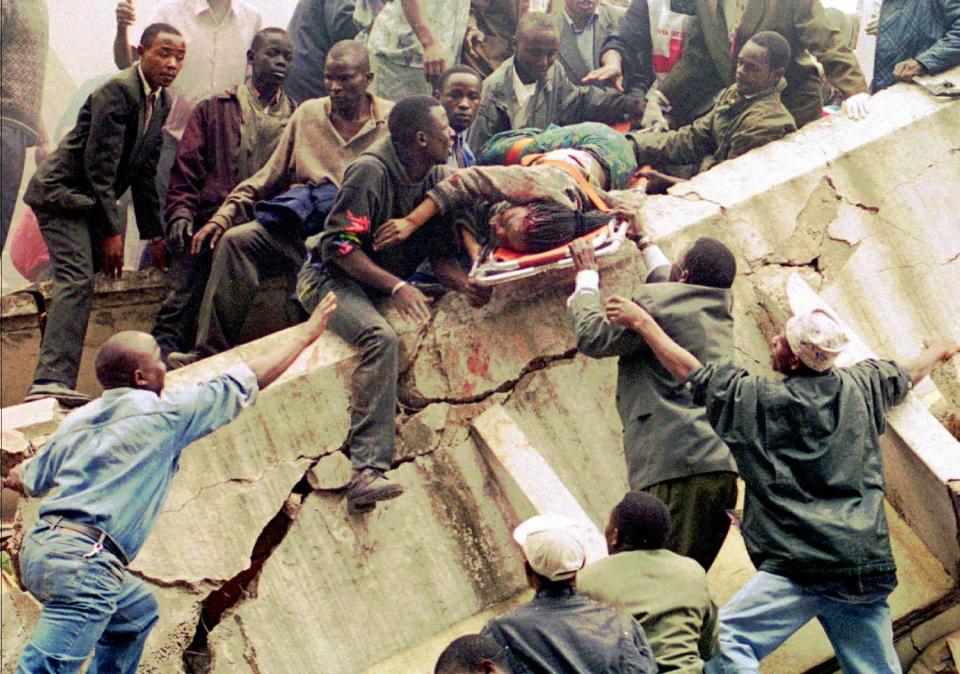 FILE - In this Friday, Aug. 7, 1998 file photo, rescue workers carry Susan Francisca Murianki, a U.S. embassy office worker, over the rubble of a collapsed building next to the embassy, in Nairobi, Kenya. In 1996, Osama bin Laden issued a formal declaration of war. But it wasn't until trucks loaded with explosives detonated outside of U.S. embassies in Nairobi and Dar es Salaam, Tanzania, killing more than 200 people on Aug. 7, 1998, that the threat became real. (AP Photo/Khalil Senosi, File)