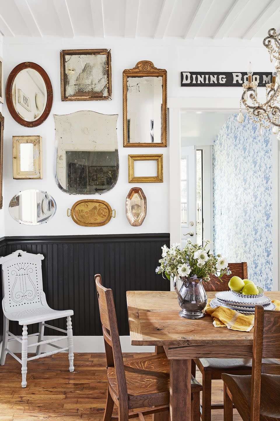 dining room with vintage display of mirrors on the wall, black wainscoting