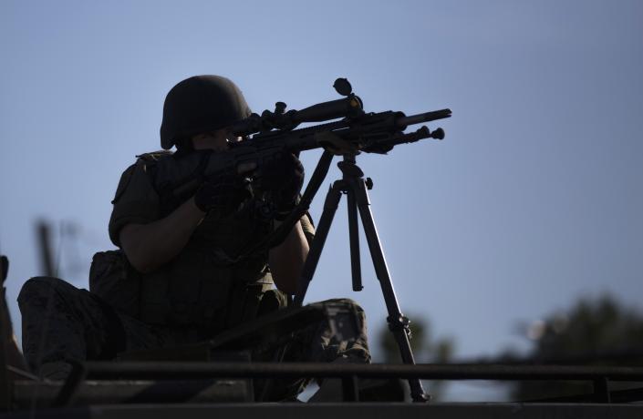 A riot police officer aims his weapon while demonstrators protest the shooting death of teenager Michael Brown, in Ferguson, Missouri, on Aug. 13, 2014. Police in Ferguson fired several rounds of tear gas to disperse protesters late on Wednesday, on the fourth night of demonstrations over the fatal shooting last weekend of Brown, 18, an unarmed black teenager by a police officer on Saturday after what police said was a struggle with a gun in a police car. A witness in the case told local media that Brown had raised his arms to police to show that he was unarmed before being killed. (REUTERS/Mario Anzuoni) 