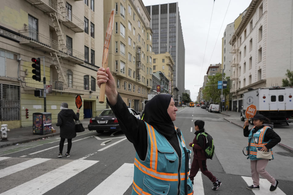 Tatiana Alabsi, center, waits for children to safely cross a street in the Tenderloin neighborhood Wednesday, April 24, 2024, in San Francisco. (AP Photo/Godofredo A. Vásquez)