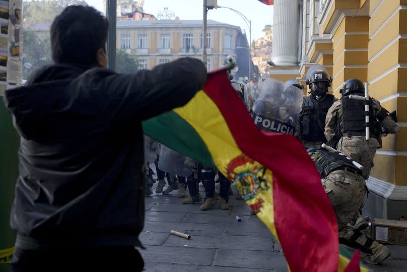A supporter of President Luis Arce waves a Bolivian flag as soldiers flee from Plaza Murillo, after a failed coup attempt, in La Paz, 26 June 2024