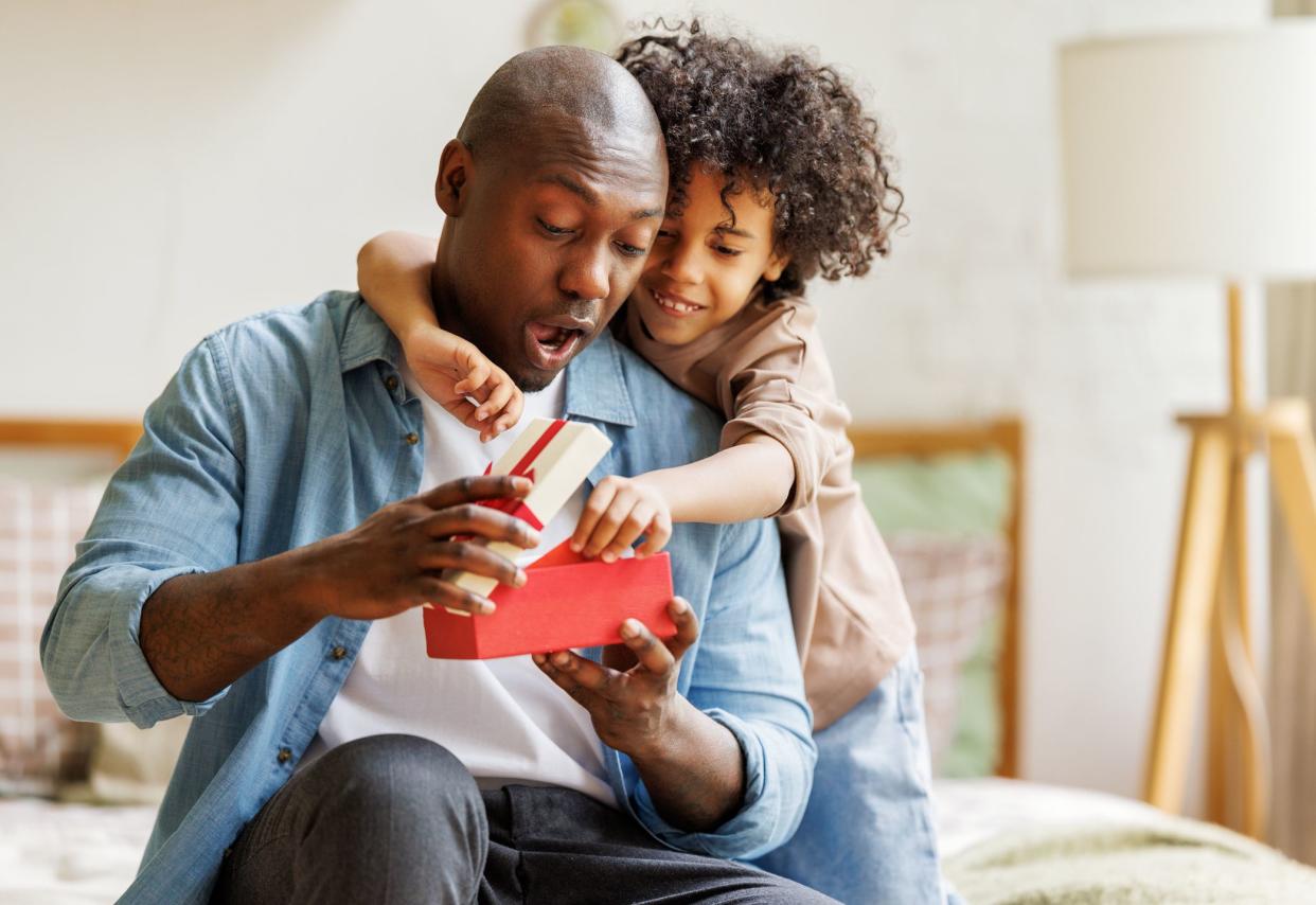 Happy Fathers day. African american kid son  giving  gift box to her dad for holiday at home