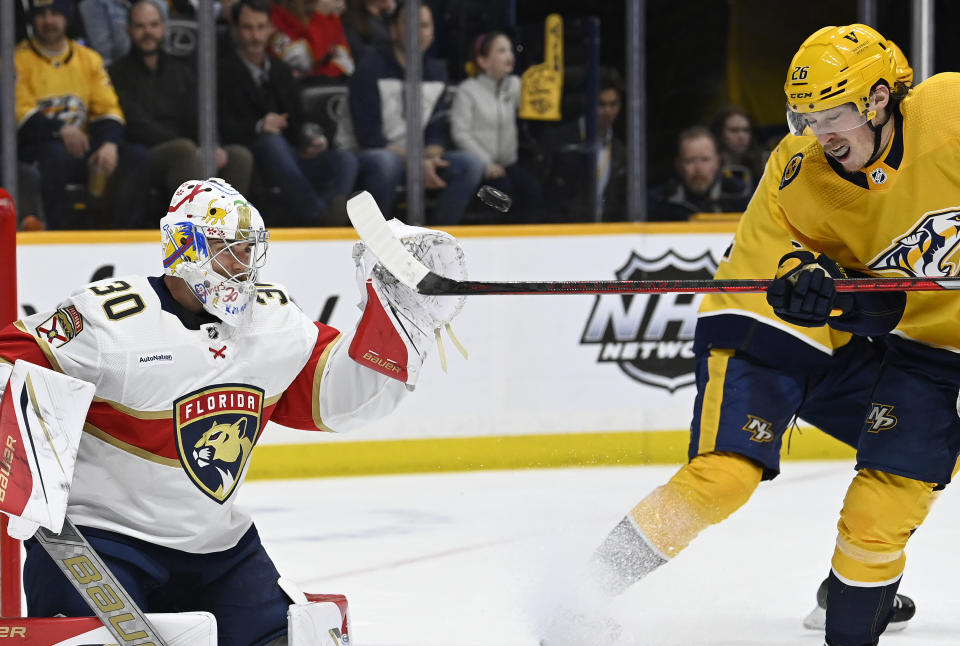 Nashville Predators center Philip Tomasino (26) tries to deflect the puck past Florida Panthers goaltender Spencer Knight (30) during the second period of an NHL hockey game Saturday, Feb.18, 2023, in Nashville, Tenn. (AP Photo/Mark Zaleski)