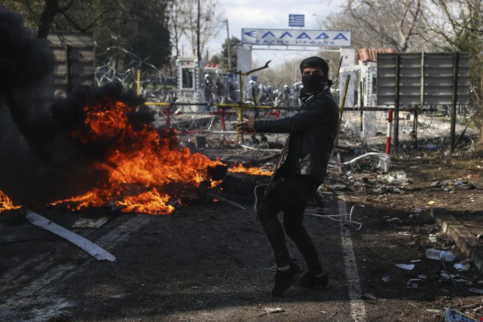 A migrant who is trying to enter Greece from the Pazarkule border gate, Edirne, Turkey, reacts as Greek riot police guard the border gate in Kastanies village, Saturday, Feb. 29, 2020. Refugees and migrants massed on the Turkish-Greek land border played a cat-and-mouse game with Greek authorities through the night and into Saturday, with border patrols using tear gas and stun grenades to stop efforts by groups of people to cross into Greece. (AP Photo/Emrah Gurel)