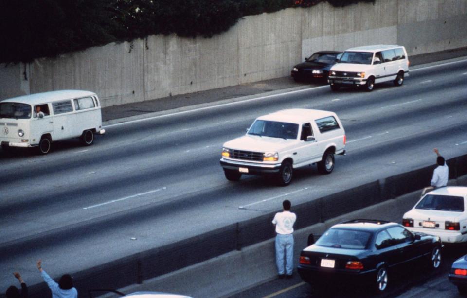 PHOTO: Motorists wave as police cars pursue the Ford Bronco (white, R) driven by Al Cowlings, carrying fugitive murder suspect O.J. Simpson, on a 90-minute slow-speed car chase June 17, 1994 on the 405 freeway in Los Angeles. (Jean-Marc Giboux/Getty Images, FILE)