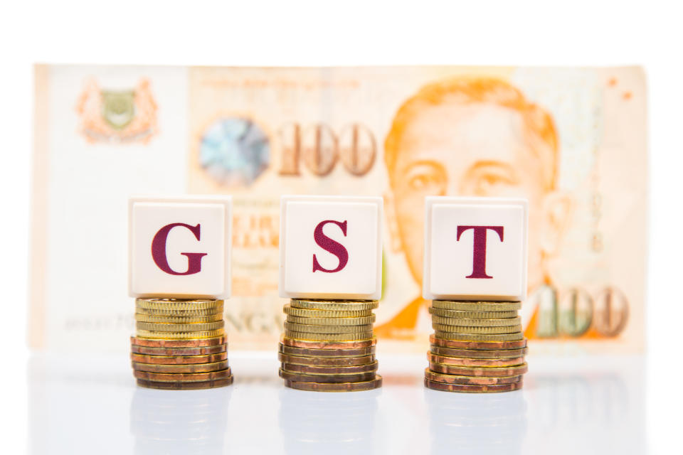 GST or Goods and Services Tax concept with a stack of coin and Singapore Dollar at the background