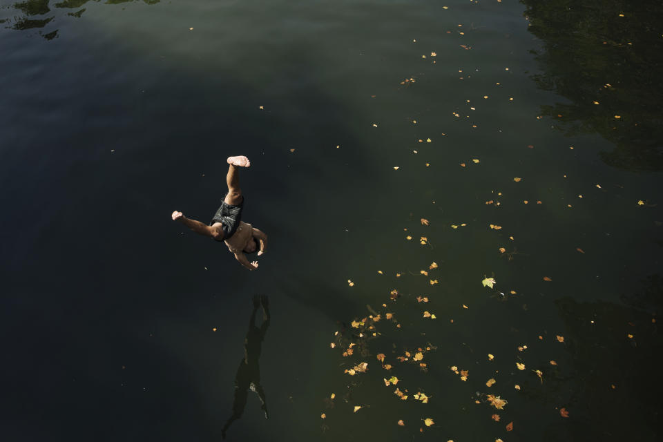 Kids jump from a bridge to swim in the Canal St Martin, during a heatwave in Paris, Monday, July 18, 2022. (AP Photo/Lewis Joly)