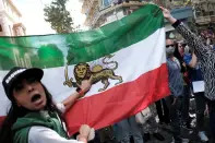 <p>An Iranian woman living in Turkey points at an old Iranian royal flag during a protest following the death of Mahsa Amini, outside the Iranian consulate in Istanbul, Turkey September 21, 2022. REUTERS/Murad Sezer</p> 