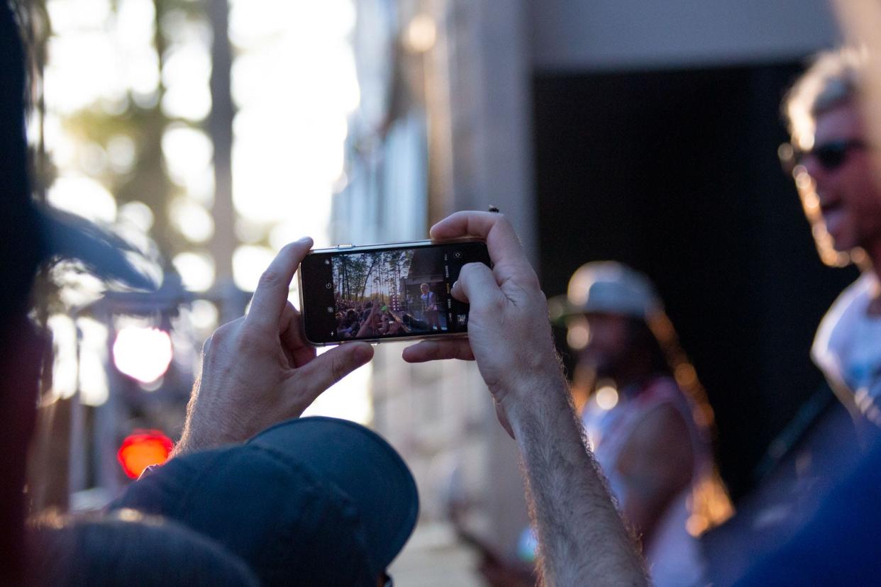 A person uses a cell phone during a Michael Franti & Spearhead concert at Greenfield Lake Amphitheater in 2019.