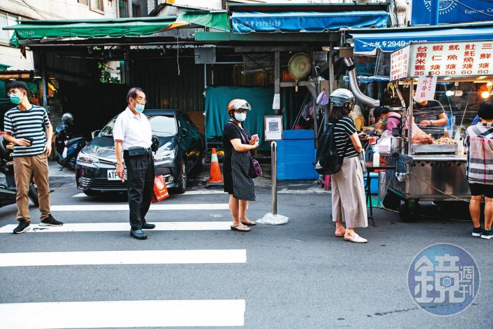 在新北市樂華夜市，民眾排隊採買依舊保持社交距離。即便月底降級，維持社交距離仍是防疫重點。