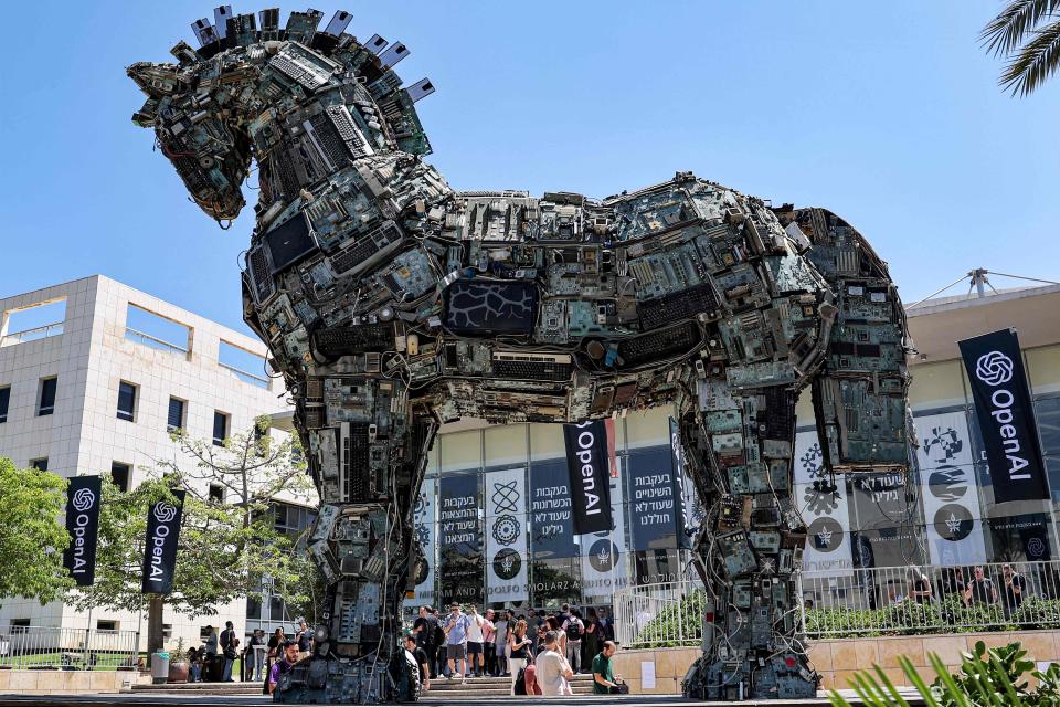 June 5, 2023:  Banners of artificial intelligence company OpenAI fly near an installation depicting the legendary "Trojan horse" built entirely out of microelectronic circuit boards and other computer components, outside at the campus of Tel Aviv University in Tel Aviv.