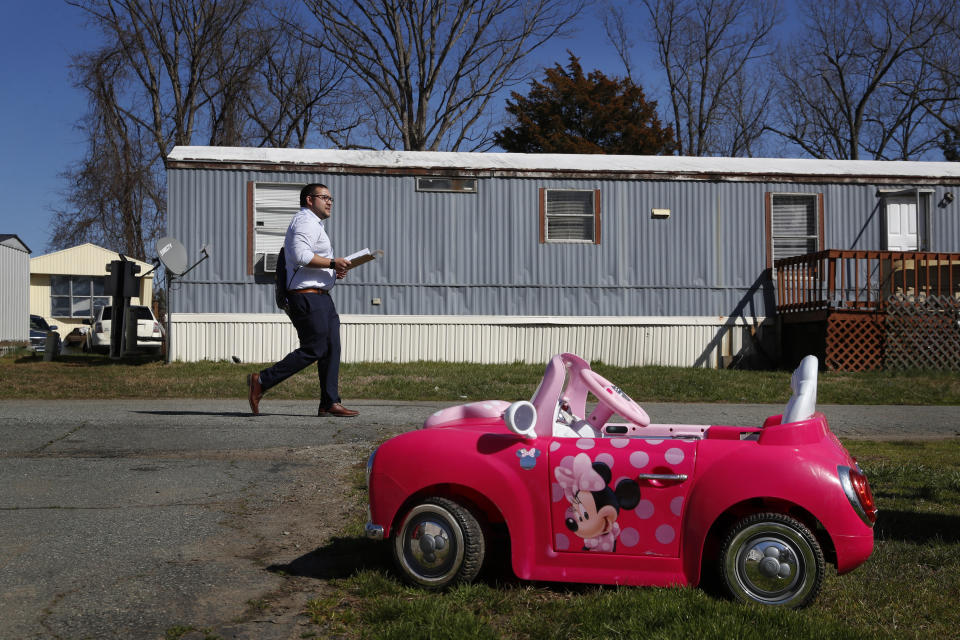 Ricky Hurtado, a Democratic candidate for the North Carolina state house, walks past a child's toy car as he canvasses in a largely Latino trailer community, in Burlington, N.C., Sunday, March 8, 2020. (AP Photo/Jacquelyn Martin)