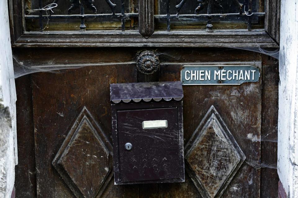 A letter box and a "Beware of the dog" sign are seen on a gate to an abandoned house. (Reuters)