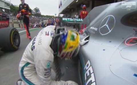 Lewis Hamilton crouches down by his Mercedees - Credit: sky sports f1