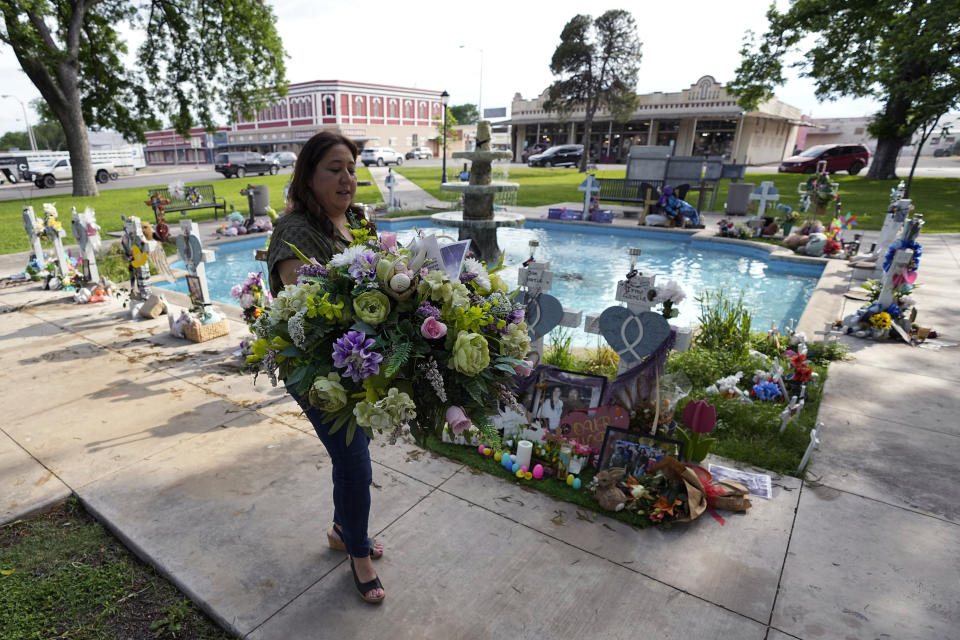 Veronica Mata recovers flowers from a memorial that honors her daughter, Tess, and other victims of the shooting at Robb Elementary School, in Uvalde, Texas, Wednesday, May 3, 2023. For Mata, teaching kindergarten in Uvalde after her daughter was among the 19 students who were fatally shot at Robb Elementary School became a year of grieving for her own child while trying to keep 20 others safe. (AP Photo/Eric Gay)