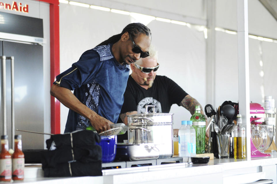 This Feb. 26, 2017 photo made available by WorldRedEye.com shows rapper Snoop Dog, left, and Chef Guy Fieri cooking together during a demonstration at the South Beach Wine & Food Festival in Miami Beach, Fla. Rappers Snoop, Action Bronson and Rev Run are ushering the culinary world into an era where shows like ““Martha and Snoop’s Potluck Dinner Party” are a hit and rappers like 2 Chainz drop cookbooks along with their albums. (Ryan Troy/WorldRedEye.com via AP)