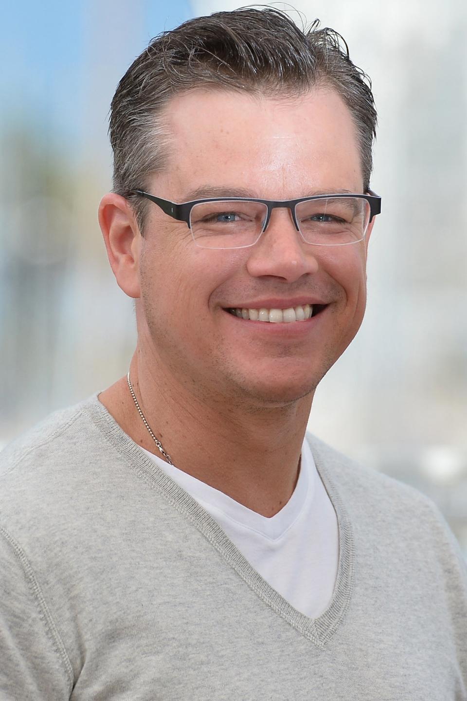 Matt smiling in a V-neck sweater, outdoors with blurry background