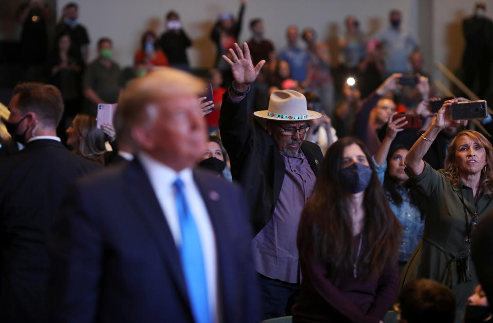 A man raises his arm in the background as Trump attends a service at the International Church of Las Vegas.