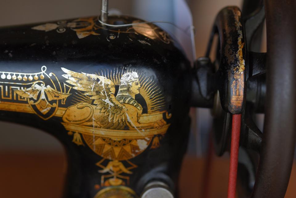Old decals with a sphinx and other Egyptian motifs decorate a 1905 Singer 127 sewing machine that John Niles is repairing.