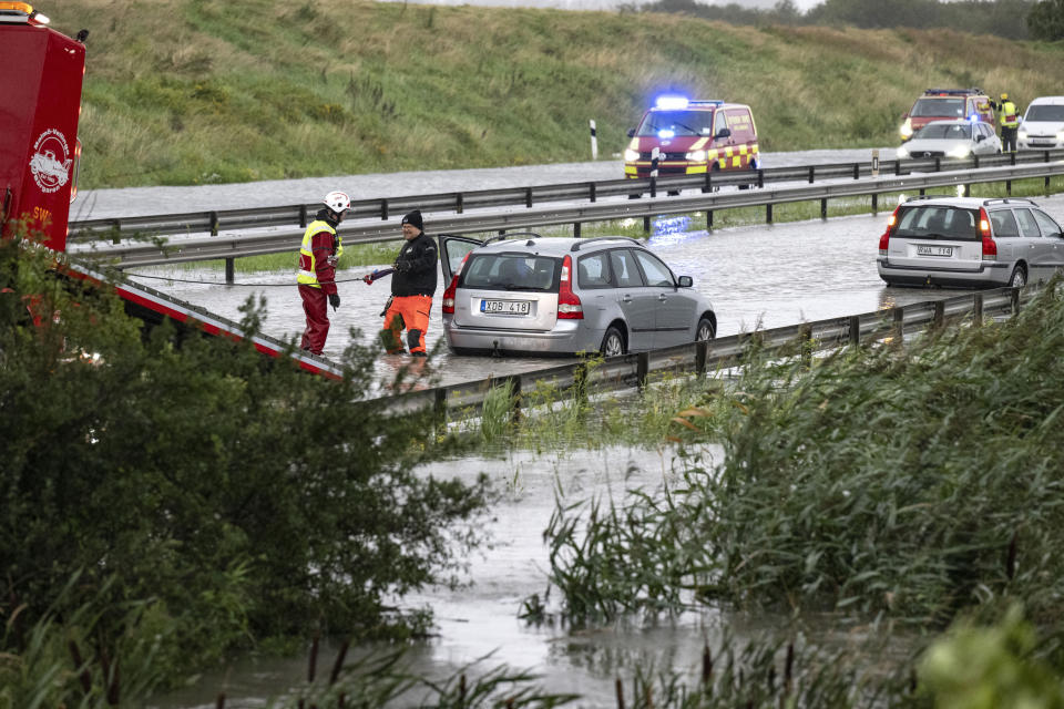 Rescue services attempt to pull out cars which got stuck in the flooded E6 road outside Malmö, southern Sweden, Monday, Aug. 7, 2023. Stormy weather across the Baltic Sea region is causing airport delays, suspended ferry service, minor power outages and lots of rain. (Johan Nilsson/TT News Agency via AP)