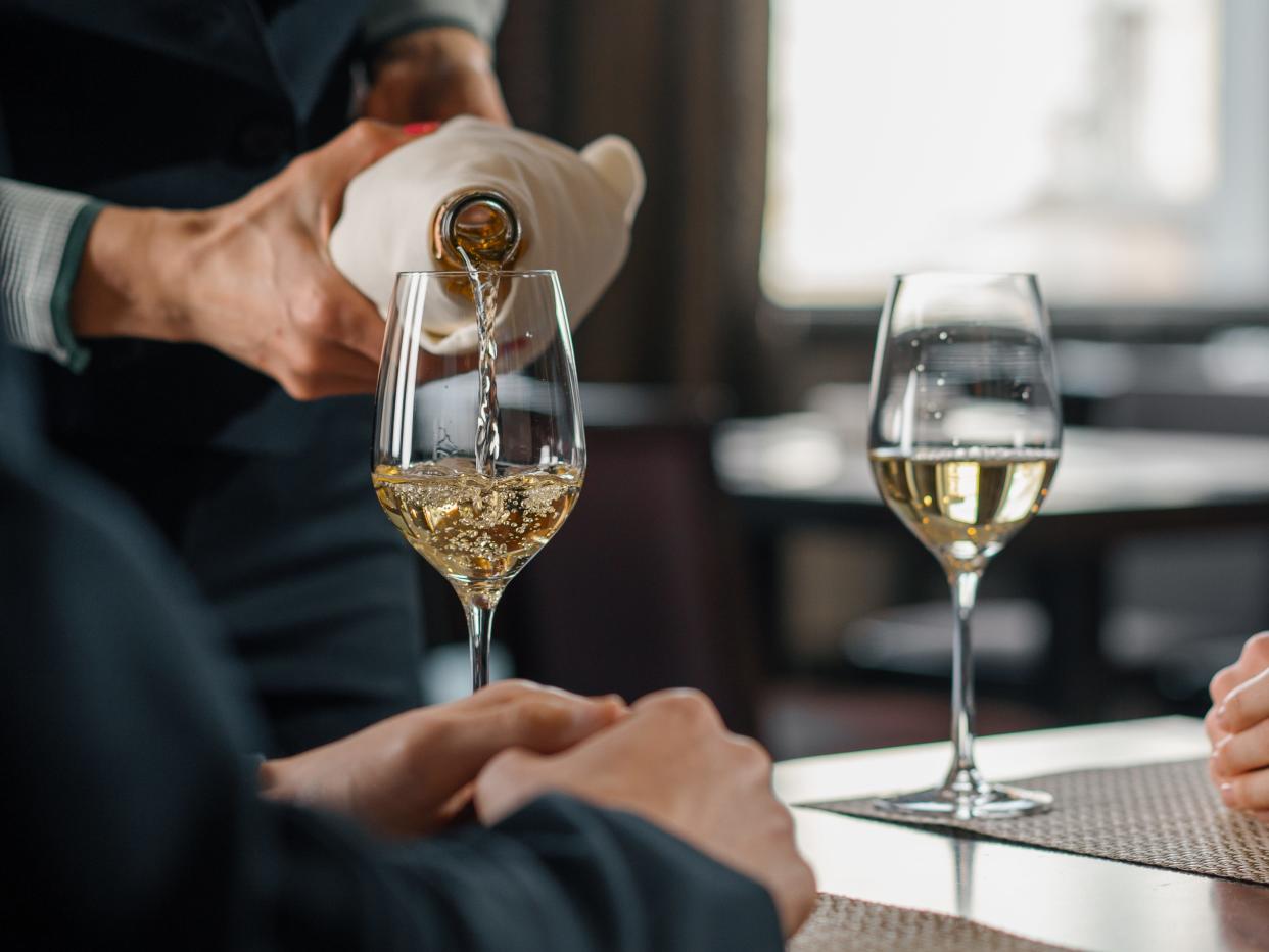 server pouring a glass of white wine