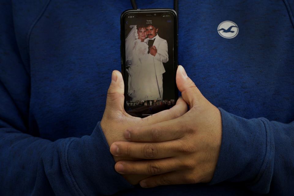 Omar Martinez holds a cellphone showing a photo of his parents' wedding.