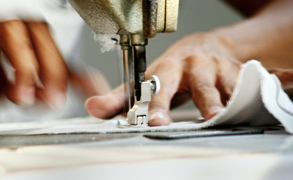 Close-up of Man Worker Sewing Clothing in Garment Factory