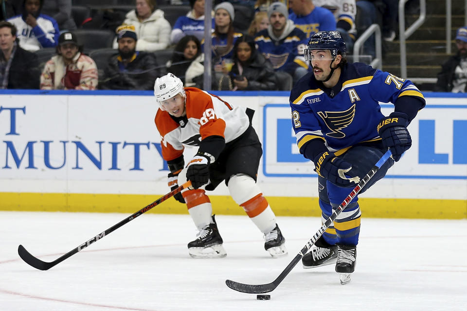 St. Louis Blues' Justin Faulk (72) controls the puck under pressure from Philadelphia Flyers' Cam Atkinson (89) during the third period of an NHL hockey game Monday, Jan. 15, 2024, in St. Louis. (AP Photo/Scott Kane)