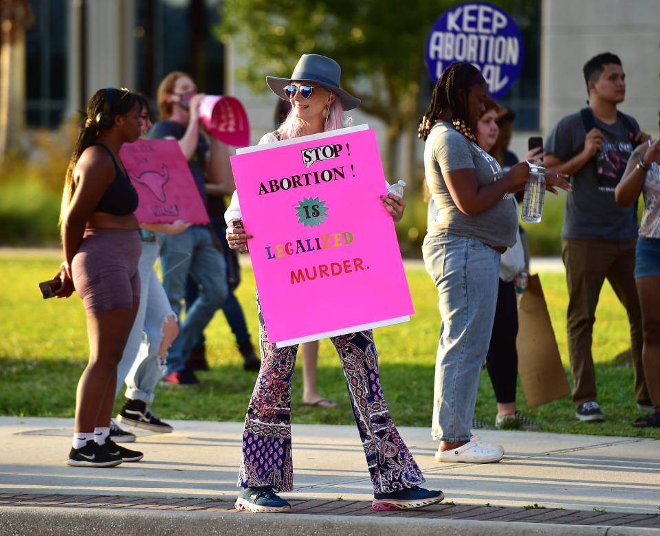 Anti-abortion protester Anna Coulter stands on the outskirts of an abortion rights rally in Jacksonville, Fla. on Wednesday, May 4, 2022.