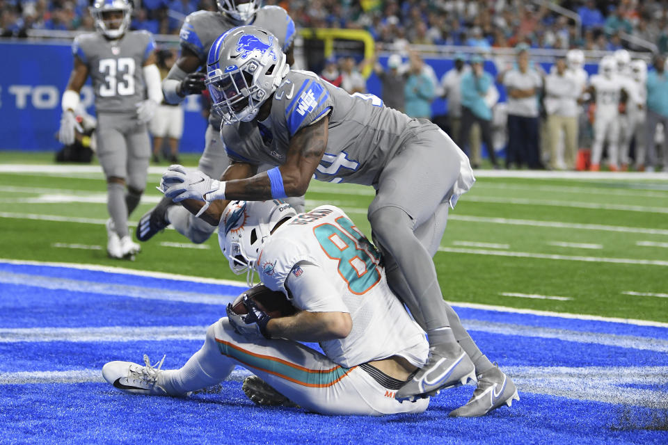 Detroit Lions cornerback Amani Oruwariye (24) falls over Miami Dolphins tight end Mike Gesicki (88) after Gesicki's 11-yard touchdown catch during the second half of an NFL football game, Sunday, Oct. 30, 2022, in Detroit. (AP Photo/Lon Horwedel)