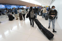 A traveler pulls a ski bag on the way to the check-in counter for United Airlines in a terminal of Denver International Airport Friday, Dec. 24, 2021, in Denver. Major airlines canceled hundreds of flights Friday amid staffing shortages largely tied to the omicron variant of the coronavirus. (AP Photo/David Zalubowski)
