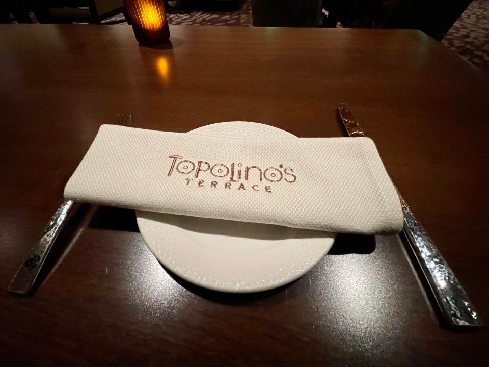 Place setting with napkin with Topolino's Terrace embroidered onto it