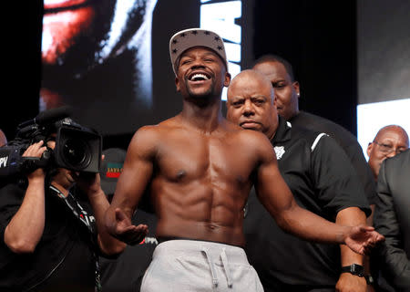 Undefeated boxer Floyd Mayweather Jr. of the U.S. laughs after posing with UFC lightweight champion Conor McGregor of Ireland during their official weigh-in at T-Mobile Arena in Las Vegas, Nevada, U.S. on August 25, 2017. REUTERS/Steve Marcus