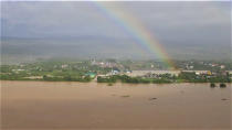 In this photo provided by the Philippine Coast Guard, a rainbow is seen above flooded areas in Cagayan valley region, northern Philippines Saturday, Nov. 14, 2020. Thick mud and debris coated many villages around the Philippine capital Friday after Typhoon Vamco caused extensive flooding that sent residents fleeing to their roofs and killing dozens of people. (Philippine Coast Guard via AP)