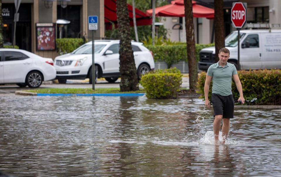 Vitali Skot of Aventura walks through ankle-deep water to get to his car in the flooded parking lot at Town Center on April 24, 2023.