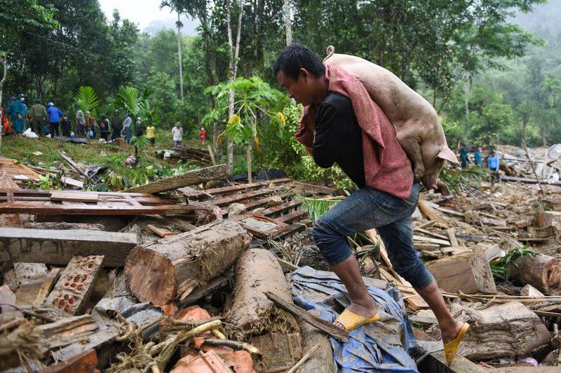 A man carries a pig saved from a landslides in Nam Tra My district