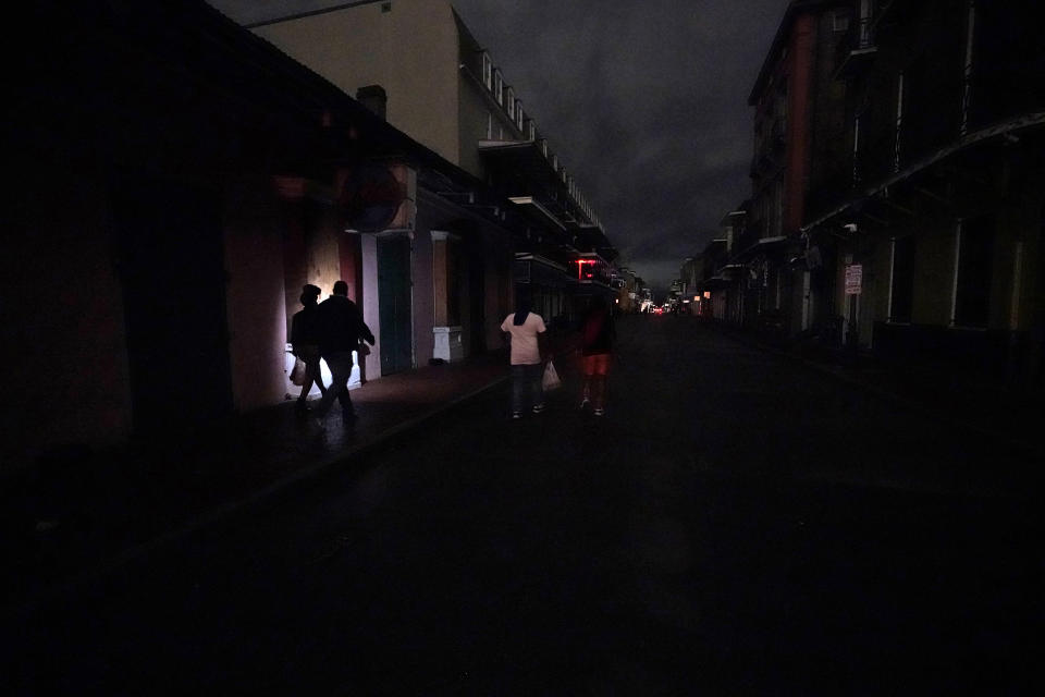 A darkened Bourbon Street is illuminated only by passers-by with lights and car headlights in the French Quarter in New Orleans, Wednesday, Oct. 28, 2020. Hurricane Zeta passed through today leaving much of the city and metro area without power. (AP Photo/Gerald Herbert)
