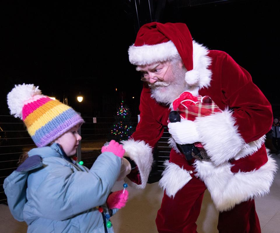 Ashlynn Fithen 4, receives Santa’s first gift during the tree-lighting ceremony following Massillon’s holiday parade last year. This year's parade and light up night is Nov. 19.