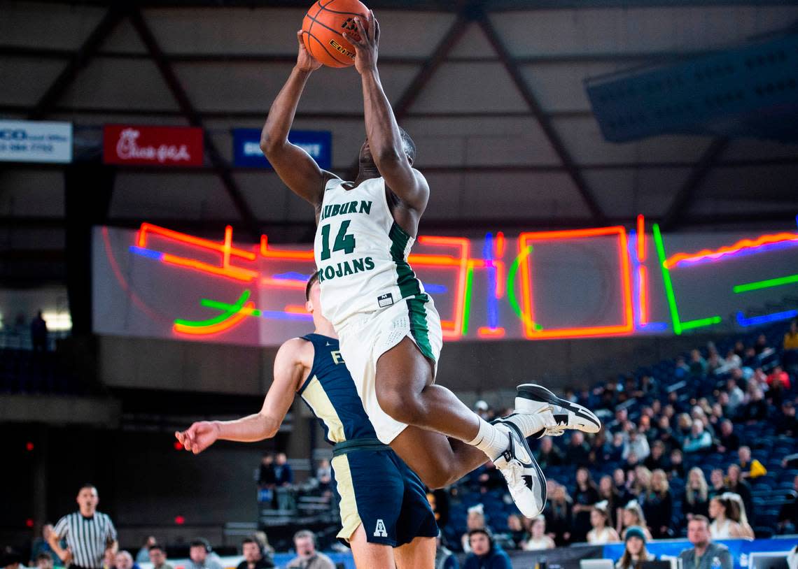 Auburn guard Luvens Valcin (14) takes a jump shot and lands on Arlington forward Jacoby Falor (5) during an opening round game at the WIAA state basketball tournament in the Tacoma Dome in Tacoma, Washington, on Wednesday, March 1, 2023. Auburn won the game 52-41.