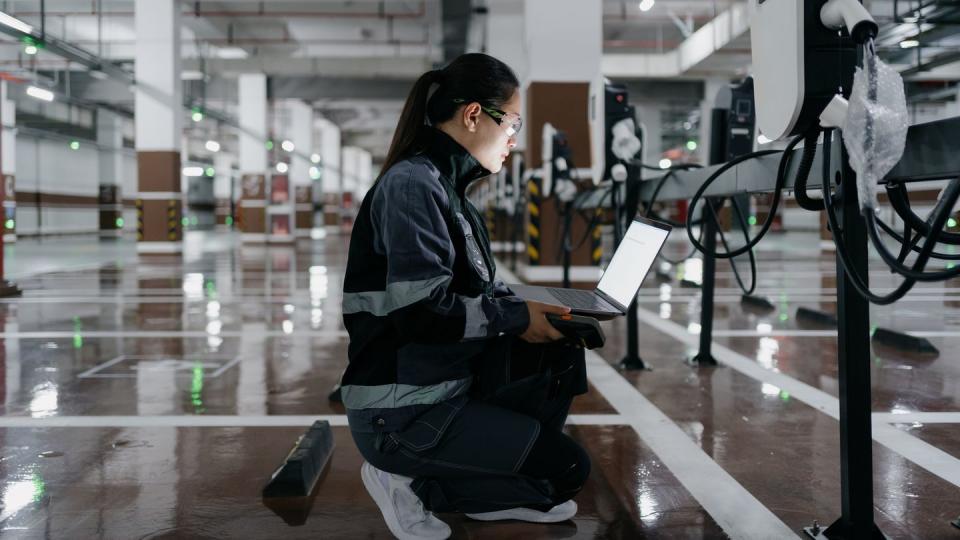 asian female engineer installing charging station in parking lot