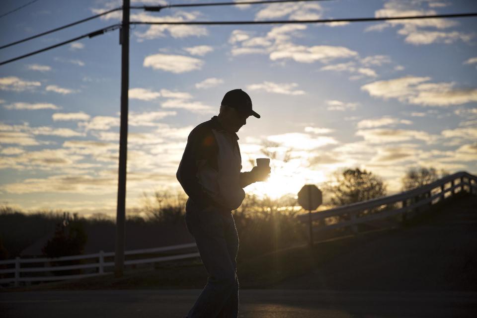 Billy Thompson walks with a cup of coffee after dropping his car off for repair as the sun rises in Lula, Ga., in Hall County, Thursday, Jan. 12, 2017. As Donald Trump prepares to enter the Oval Office, citizens with disparate views from urban and rural areas illustrate the widening cultural fissures that help explained Trump's rise and will define his presidency. (AP Photo/David Goldman)