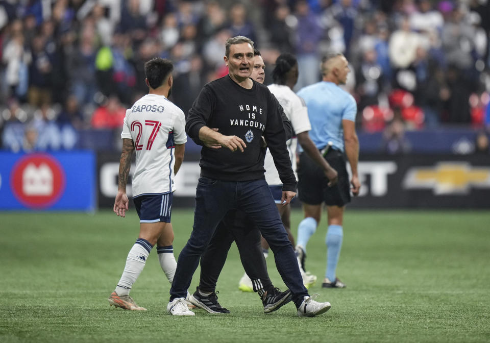 Vancouver Whitecaps head coach Vanni Sartini, center front, is restrained by a member of the team's staff after he went on the field and tried to get to referee Tim Ford after receiving a red card during the second half in Game 2 of a first-round MLS playoff soccer match against Los Angeles FC in Vancouver, British Columbia, Sunday, Nov. 5, 2023. (Darryl Dyck/The Canadian Press via AP)