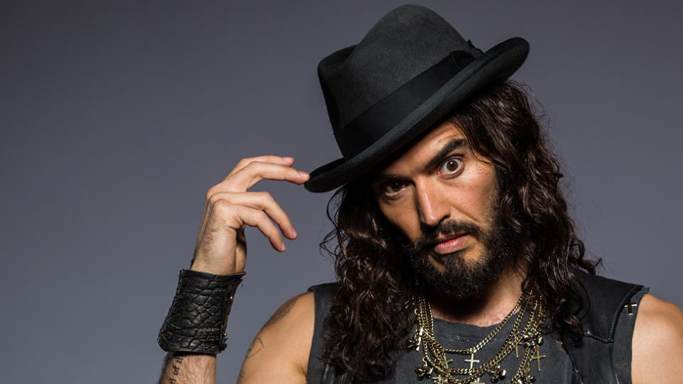 Russell Brand poses in a hat with long hair