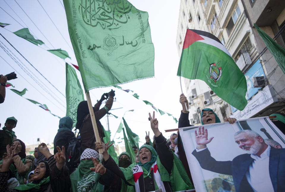 FILE, Palestinian women, one holding a picture of Hamas movement chief, Ismail Haniyeh, attend a mass rally marking the 32nd anniversary of the founding of Hamas, an Islamic political party that currently rules in Gaza, Saturday, Dec. 14, 2019, in Gaza city. As a rising number of Gazans are drowning in the sea en route to a better life in Europe, Gaza's Hamas rulers are moving to comfortable life in upscale Middle East hotels, prompted a rare outpouring of anger at home, where the economy collapses and 2.3 million people remain effectively trapped in the tiny, conflict-scarred territory. (AP Photo/Khalil Hamra, File)