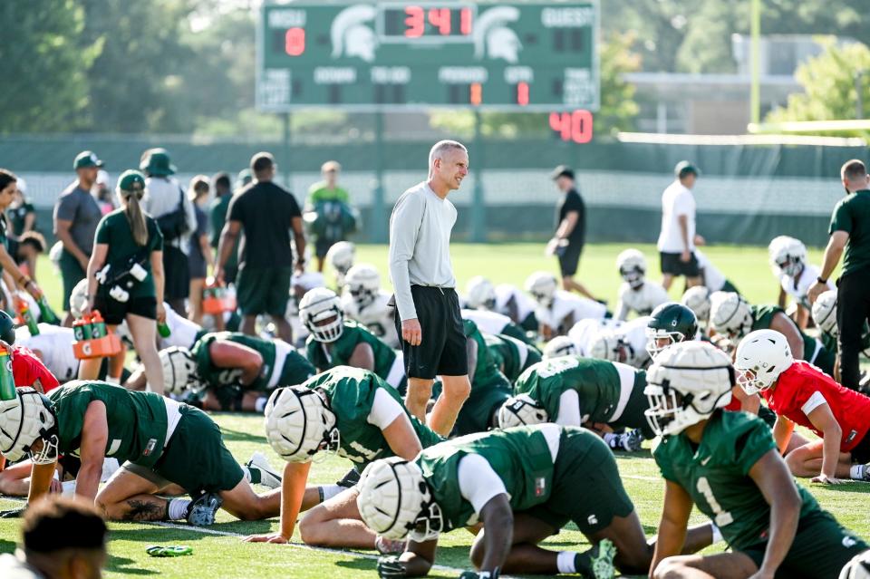 Michigan State's offensive coordinator Jay Johnson, center, walks among the players during the opening day of MSU's football fall camp on Thursday, Aug. 3, 2023, in East Lansing.