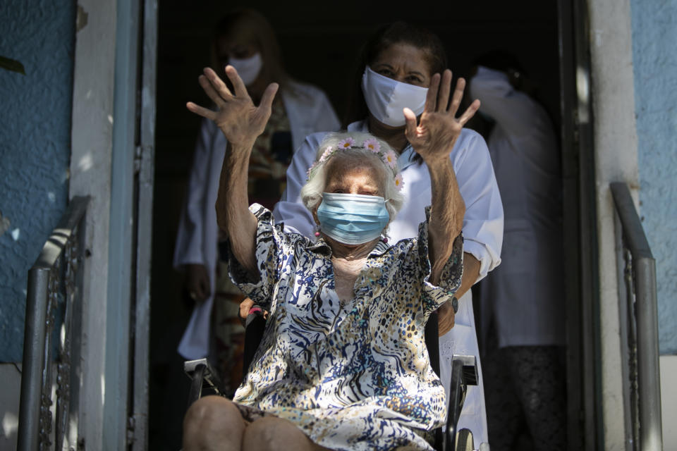 Zelia de Carvalho Morley, 106, waves before receiving a shot of China's Sinovac CoronaVac vaccine for the new coronavirus at the retirement home where she lives in Rio de Janeiro, Brazil, Wednesday, Jan. 20, 2021. De Carvalho Morley lived through the 1918 flu pandemic. (AP Photo/Bruna Prado)