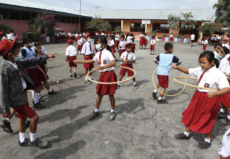 Students wearing masks to protect themselves from volcanic ash from Mount Sinabung eruption, as they play with rattan rings at their school at Tiganderket village in Karo district, Indonesia, outside of the evacuation zone. (Reuters)